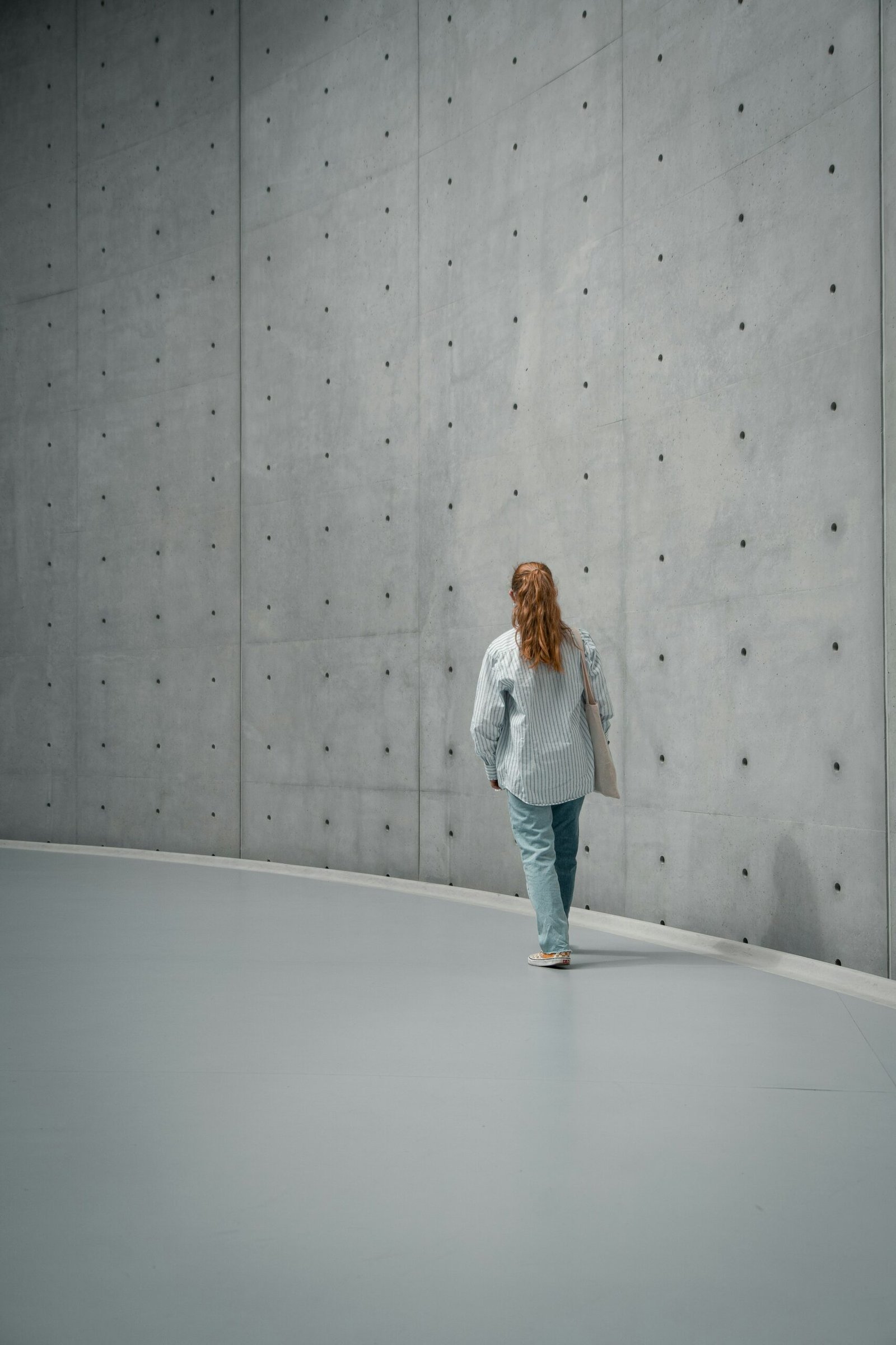Mulher caminhando em corredor curvo de concreto
